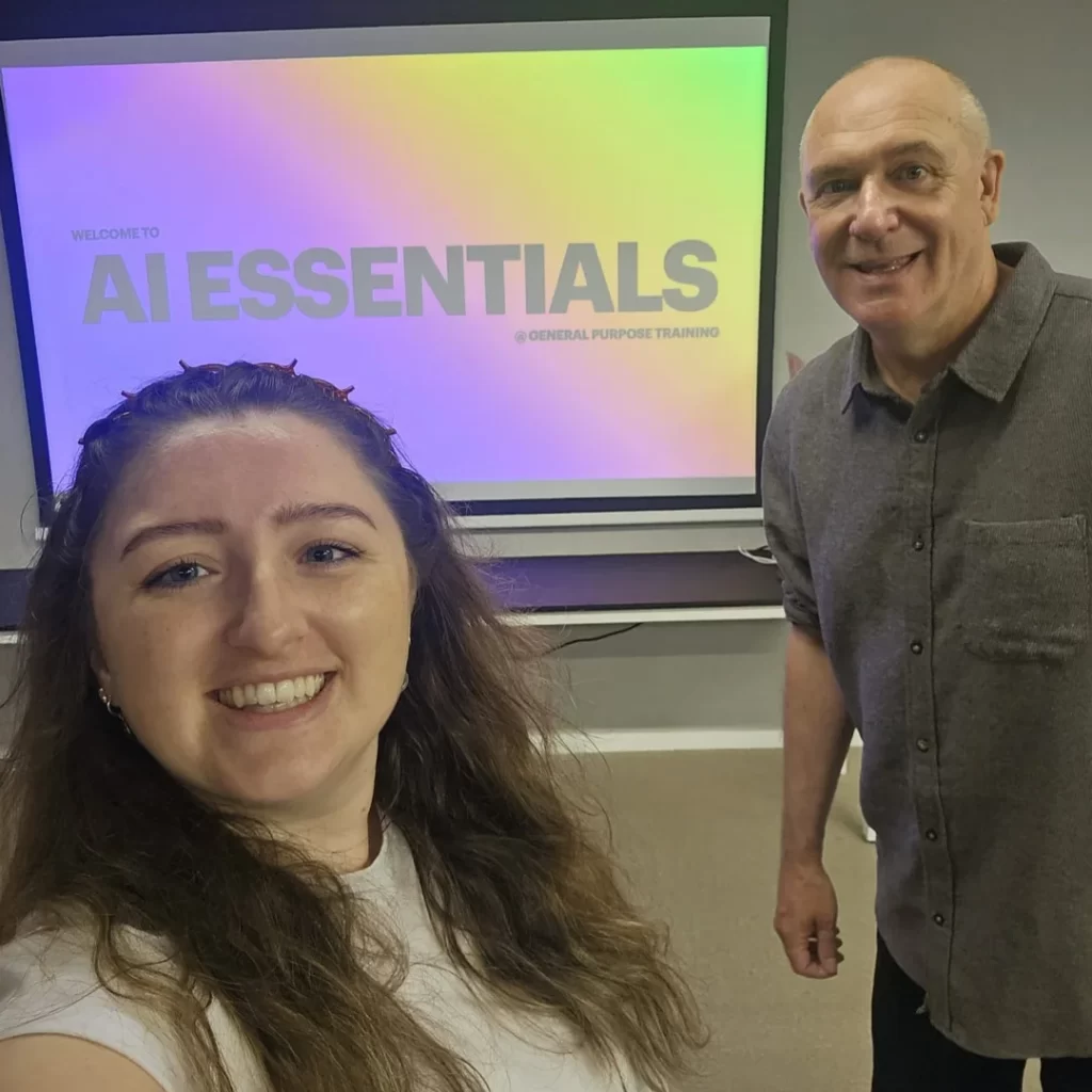 Kirstie Kavanagh and Glenn White smiling in front of a screen reading "AI Essentials" during a professional training session for General Purpose Training.